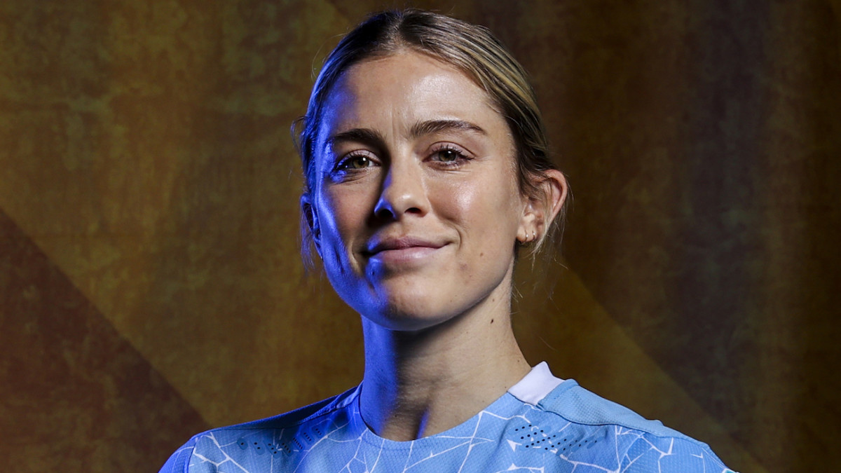 Abby Dahlkemper poses in a light blue soccer jersey and wears her dirty blonde hair in an up-do.